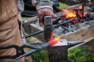 Twisting a red-hot billet is clamped in the grip. Blacksmith twists a hot rod on the anvil.