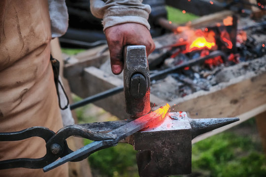Twisting a red-hot billet is clamped in the grip. Blacksmith twists a hot rod on the anvil.