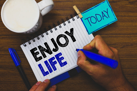 Word writing text Enjoy Life. Business concept for Any thing, place,food or person, that makes you relax and happy Man holding marker notebook clothespin reminder wooden table cup coffee