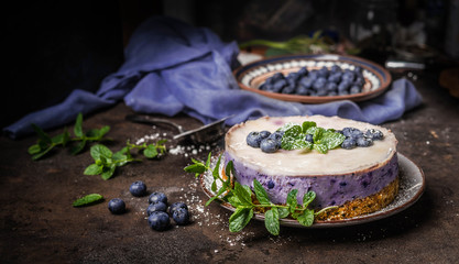 Vegan blueberry cake on dark rustic kitchen table background with fresh berries, side view. Healthy food