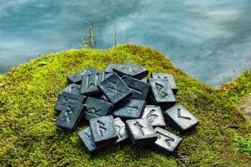 24 Norse runes on the green grass and the evening river background