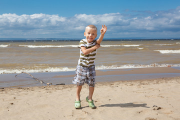 Portrait of happy little kid boy on the beach of ocean. Funny cute child  enjoying summer.