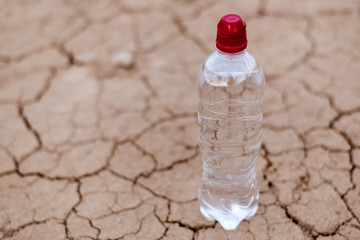 A bottle of water on the dried, cracked soil.