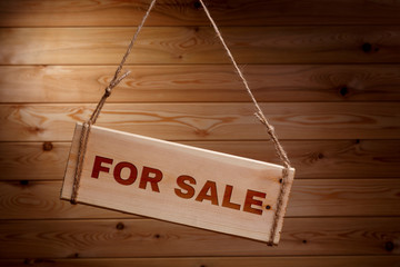 Wooden signboard with the words FOR SALE on a rough rope on a beautiful wooden background