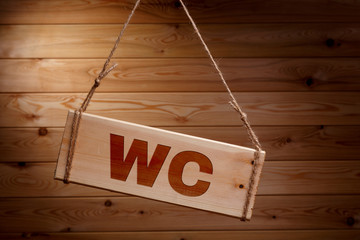 Wooden signboard with the words WC on a rough rope on a beautiful wooden background