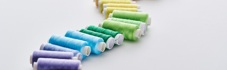 panoramic shot of bright and colorful threads on white background