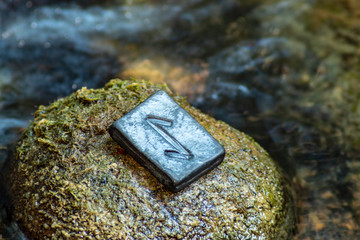 Norse rune Eihwaz on the stone and the evening river background. Abruptness, changes, news.