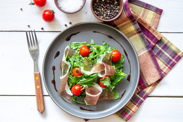 Salad with arugula, tomatoes and prosciutto. Italian cuisine. Healthy eating. Diet.