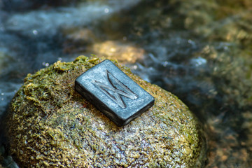 Norse rune Dagaz (Dagr) on the stone and the evening river background. Dawn, transformation, quick changes to the good.