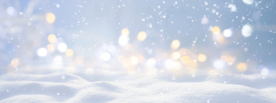 Festive Christmas natural snowy landscape, abstract empty stage, background with snow, snowdrift and defocused Christmas lights. Blue and yellow Golden Christmas lights against blue sky, copy space.