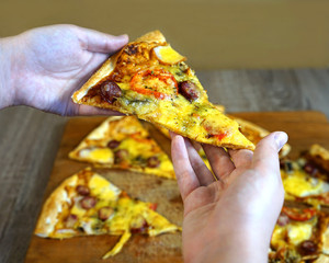  A girl in a fast-food restaurant picks up a piece of pizza in front of a table with the rest of...