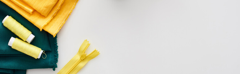 panoramic shot of fabric, zipper and threads on white background