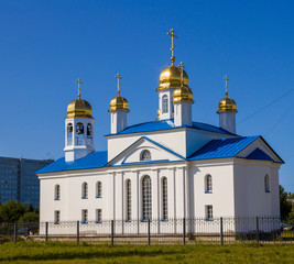 Orthodox Church with bells and domes behind the fence