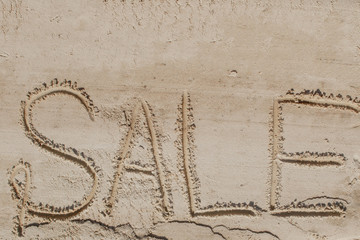 The word sale is painted on the sand. Beach background. View from above. The concept of summer, summer kanikkuly, vacation, holydays.