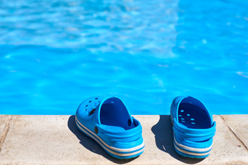 Fototapeta na wymiar Blue flip flops near the swimming pool, close up