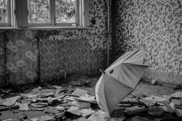 Broken umbrella in an empty room with ragged wallpapers in an abandoned house. Black and white