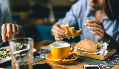 close up shoot of cup of coffee. people eating in blurred background