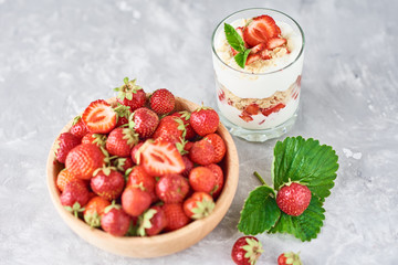 Strawberry granola or smoothie in glass and fresh berries in a wooden bowl. Healthy breakfast