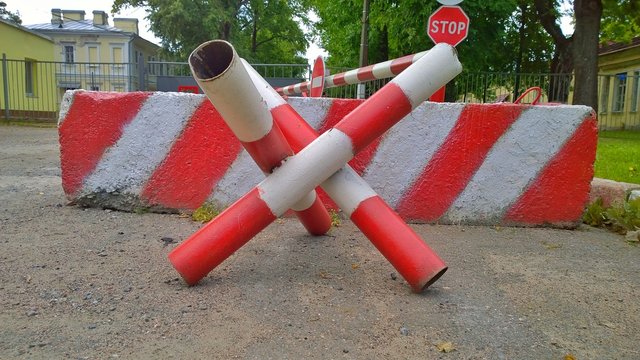 Barrier. Passage is closed. Driveway closed. Entry is prohibited. Protected and restricted area, limits. Red and white striped concrete road barriers lying on the asphalt pavement.