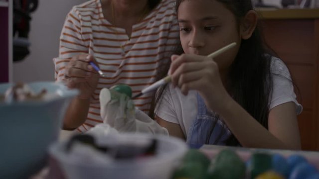 Asian girl and her mother are making crafts from the egg shells, Mother helping her daughter painting egg shells together at home, Education concept.