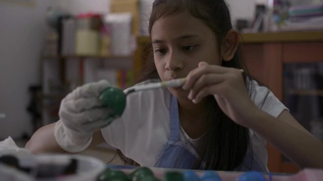 Asian cute girl is making crafts from egg shells on the desk, Young girl is coloring egg shells at home for her homework, Education concept.