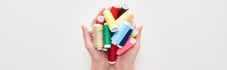 cropped view of woman holding bright and colorful threads on white background