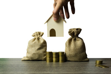 Fototapeta na wymiar Saving money, home loan, mortgage, a property investment for future concept. A man hand a small residence house over stack of coins pile and money bag on wood table. A sustainable investment.