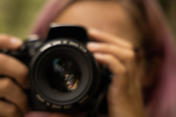 unfocused blurred concept female portrait of incognito photographer with black digital camera 