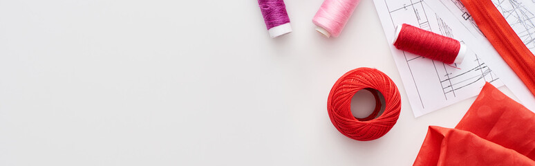 panoramic shot of colorful threads, knitting yarn ball, fabric, sewing patterns and zipper on white background © LIGHTFIELD STUDIOS