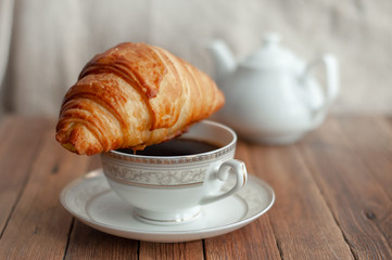 Croissant and a Cup of tea coffee on a wooden table