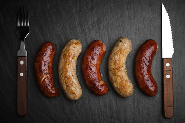 grilled chicken and beef sausages on black stone. top view
