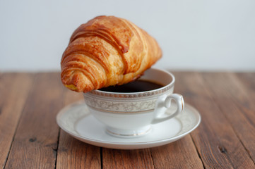 Croissant and a Cup of tea coffee on a wooden table