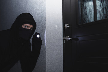 burglar in mask ready to break in the house at night