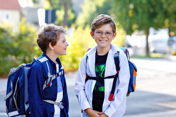 Two little kid boys with backpack or satchel. Schoolkids on the way to school. Healthy adorable...