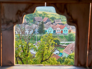 Traditional houses in Transylvania, Romania, seen through a frame in the Alma Vii fortified church stone wall.