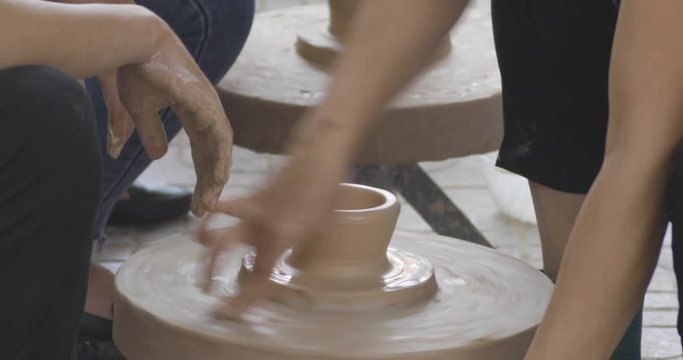 closeup on potter's hands shaping clay on a spinning pottery wheel