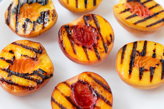 Homemade grilled peaches on a white plate, low angle view. Close-up.