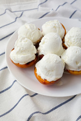 Homemade grilled peaches with vanilla ice cream on a white plate, low angle view. Close-up.