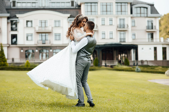 Young loving couple hugging and dancing on the green grass. Beautiful and happy woman and man gently touch each other. Beautiful couple in love. girl in the dress and the guy in the shirt.