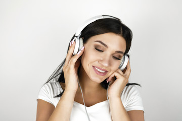 Fototapeta premium brunette young woman listening her favourite music in headphones feeling satisfied on isolated white background