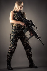 luxurious blonde in uniform with machine gun in hands