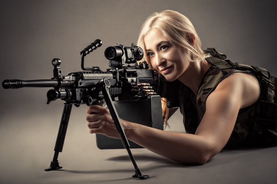 Beautiful Blond Woman Aiming Machine Gun While Lying On The Floor