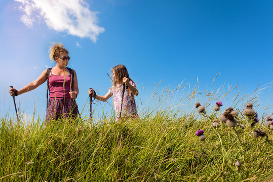 beautiful girl and her mom doing nordic walking with sticks in the countryside