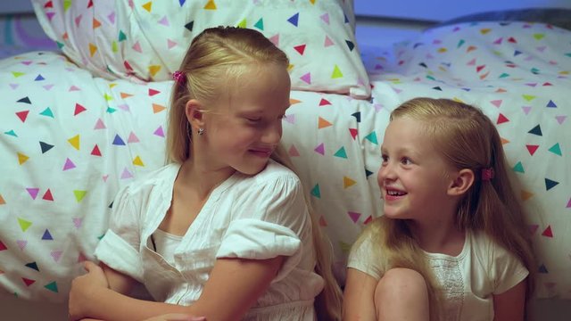 Happy reconciliation and hug of two sisters sitting at home. Girlfriends reconciling after quarrel and promise to be best friends forever