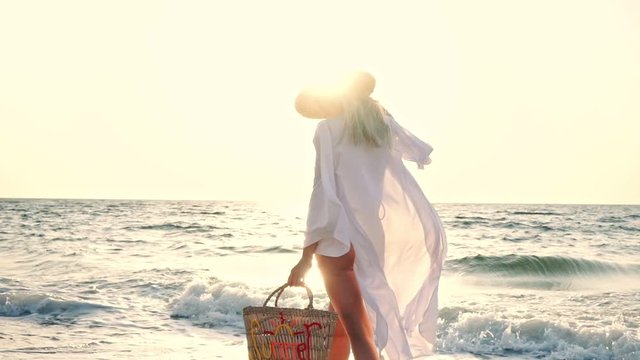 Gorgeous blonde woman 20s in summer straw hat walking outdoors on the beach