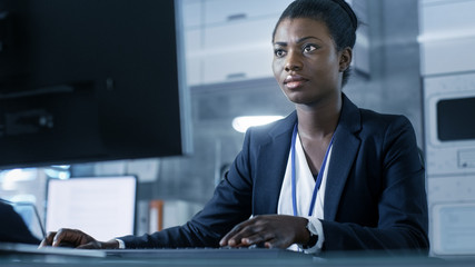 African-American Female Scientist Working on a Computer with Her Colleagues at Research Center.