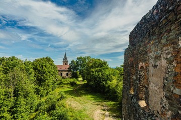 Krasikov, Kokasice / Czech Republic - August 9 2019: Remains of stone Svamberk castle from 13th century and church of Mary Magdalene. Bright sunny day with blue sky and white clouds. 