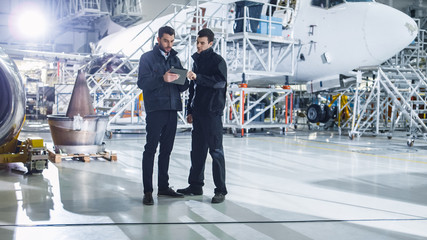 Team of Aircraft Maintenance Mechanics Looking at Airplane