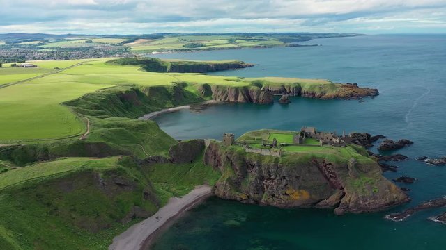 Aerial view of Dunnottar Castle, ruined medieval cliff top fortress located upon rocky headland protruding from sea - panorama of Scotland from above, United Kingdom, Great Britain, Europe