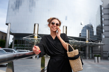 Woman in black dress and sunglasses talking on the phone